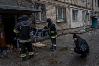 Сотрудники городской службы забирают тело женщины, погибшей в результате обстрела. Справа на фотографии — ее дочь. С 20 по 25 ноября, по <a href="https://www.facebook.com/khersoncouncil/videos/883864869276674/" rel="noopener noreferrer" target="_blank">сообщению</a> главы военной администрации освобожденного Херсона Галины Луговой, из-за российских ударов по городу погибли 15 мирных жителей, в том числе один ребенок