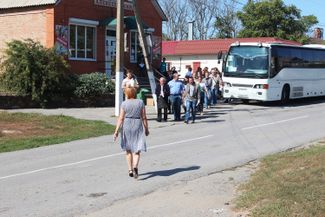 A volunteer from a polling station greeting DNR residents as they get off the bus in Matveyev Kurgan