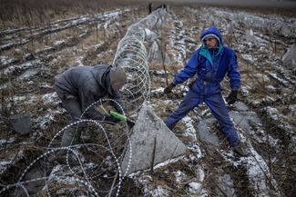 Рабочие устанавливают «зубы дракона» на линии обороны