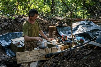 Украинский солдат варит кофе, пока его сослуживцы укрепляют траншеи