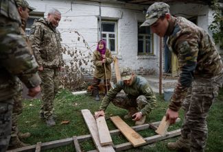 78-летняя Евдокия Безнощенко разговаривает с военнослужащими ВСУ, которые помогают ей с ремонтом дома в зоне отчуждения