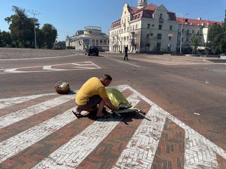 Житель Чернигова накрывает тело одного из погибших во время российского обстрела