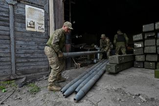 Военнослужащие ВСУ готовят снаряды для ракетной системы, установленной на обычном пикапе