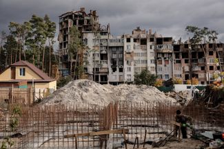 Рабочие строят новый дом на месте здания, разрушенного в ходе боевых действий в марте 2022 года