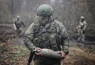 Военнослужащий российской армии несет снаряд для гаубицы Д-30, чтобы вести огонь по украинским позициям