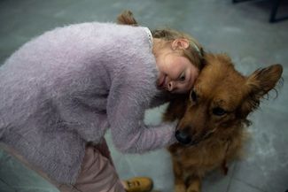 Девятилетняя Варвара Загуменная обнимает собаку по кличке Челси во время сеанса канистерапии в центре Vcentri Hub в Киеве. Канистерапия — метод лечения и реабилитации, при котором людям помогают собаки. Их специально отбирают и учат общению с пациентами. В Украине канистерапию предлагают в том числе детям бойцов ВСУ — как действующих, так и погибших