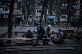 Жители Херсона обрабатывают доски во время ремонта одного из поврежденных зданий