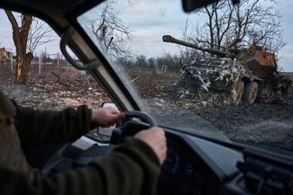 Украинские военные проезжают мимо разбитой артиллерийской установки. 14 февраля 2024 года