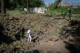 Житель Бахмута осматривает воронку, появившуюся после падения российской ракеты. Глава Лисичанска Сергей Гайдай называл трассу Лисичанск — Бахмут «дорогой жизни»: по ней доставляли гуманитарные грузы и эвакуировали жителей. В конце недели Гайдай рассказал, что трасса «непроездная» и полностью обстреливается российскими войсками. Однако возможность доехать до Лисичанска по параллельному маршруту остается