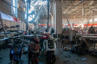 Police officers and territorial defense officers gathering products in a store that’s been hit by bombs. March 15