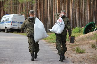 Солдаты несут мешки с найденными на месте раскопок останками, Сандармох, 29 августа 2018 года