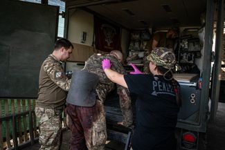 Военные медики ведут раненого в эвакуационную машину