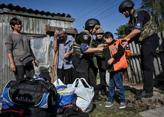 Полицейские надевают защитный жилет на 10-летнего Дмитрия перед эвакуацией из поселка Степногорск, расположенного в нескольких километрах от линии фронта. В <a href="https://uatv.ua/zhizn-na-linii-fronta-kak-volontery-pomogayut-mestnym-zhitelyam-stepnogorska-zaporozhskoj-oblasti/" rel="noopener noreferrer" target="_blank">поселке</a> нет электричества, газа и воды, он регулярно подвергается российским обстрелам