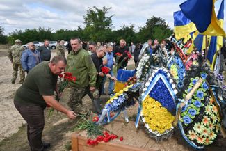 Люди возлагают цветы на «Аллее славы» на кладбище Изюма