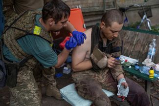 Украинский военный врач с позывным Йода помогает своему раненому сослуживцу