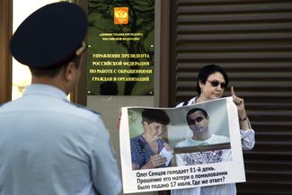 A woman holds a poster during an individual picket outside the offices of the Russian presidential administration. Her poster reads, “Oleg Sentsov is on the 81st day of his hunger strike. His mother petitioned for a pardon on July 17. Where is the answer?” Moscow, August 2, 2018.