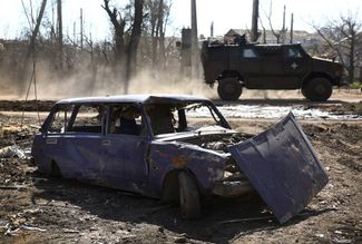 Бронированная военная машина ВСУ проезжает через Часов Яр, мимо разбитого гражданского автомобиля. Через Часов Яр, который находится в 13 километрах от Бахмута, проходит ключевая линия снабжения подразделений ВСУ