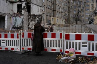 A woman stands near the destroyed section of the building 