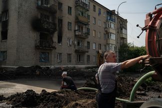 Рабочие отводят воду из воронки, образовавшейся после взрыва