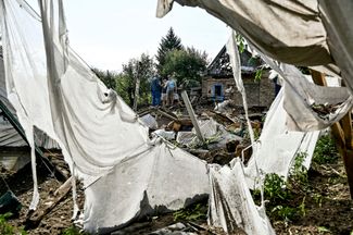 Жители поселка Кушугум Запорожской области во дворе разрушенного дома. Российский снаряд упал сюда во время ночного обстрела, оставив огромную воронку. О погибших и пострадавших не сообщается