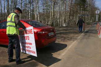 Alexander Kokin, the head of the administration in the Tumbotino workers' settlement, holds up a sign that says "Warning! Quarantine!"