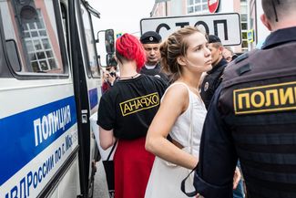 A protester is arrested wearing a shirt that says “anarcho,” or “security” in reverse.