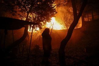 Жительница Харькова на фоне пожара в секторе частной застройки, вызванного атакой российского дрона