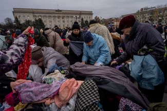 Жители Херсона выбирают себе одежду среди пожертвованных вещей на пункте раздачи гуманитарной помощи