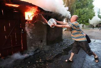 Житель Лидиевки тушит здание, загоревшееся в результате обстрела