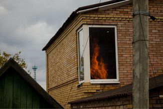 Огонь от пожара в Бахмуте отражается в целом окне стоящего напротив здания