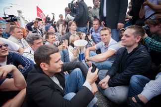 On May 6, 2012, Navalny helps stage a mass protest at Moscow’s Bolotnaya Square against Vladimir Putin’s re-election and return to the presidency. In this photo, Navalny joins two of the demonstration’s other leaders, Boris Nemtsov and Ilya Yashin, in staging a sit-in. The rally ends in clashes with the police and dozens of criminal cases alleging riots and violence against the police. These investigations later became known collectively as the “<a href="https://meduza.bypassnews.online/feature/2017/05/06/pyat-let-bolotnomu-delu-desyat-istoriy-ego-uchastnikov" target="_blank">Bolotnoye Delo</a>.”