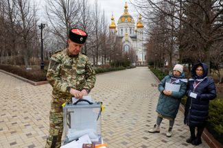 «Избирательная комиссия» наблюдает за голосованием на улице в Донецке, 10 марта 