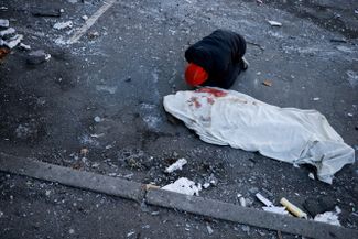 A man mourns next to the body of his mother, who was killed as the result of rocket fragments hitting a residential building.