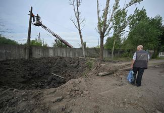 Житель Дружковки возле воронки, которая образовалась из-за российского ракетного удара