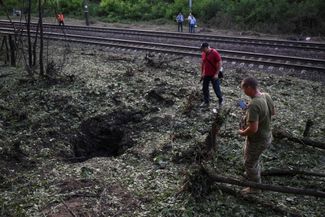 Жители Запорожья осматривают воронку на месте падения российской ракеты