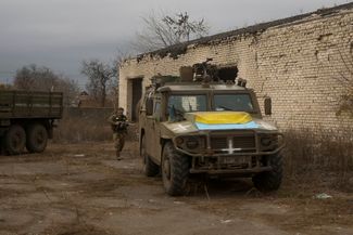 Украинский военный рядом с захваченным российским бронетранспортером в селе Благодатное.