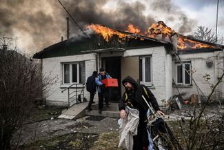 Люди бегут с вещами из своего дома в Ирпене, по которому пришелся авиаудар. 4 марта 2022 года