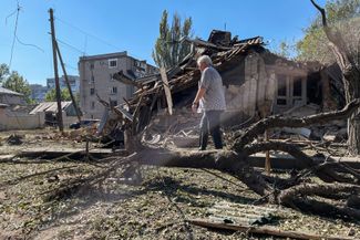 Житель Херсона идет мимо дома, разрушенного российской ракетой