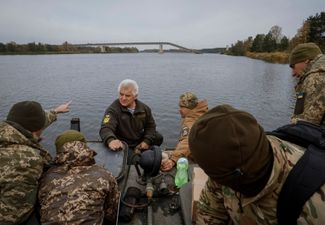 Украинские военнослужащие на лодке добираются до сел в чернобыльской зоне отчуждения. Они доставляют туда продовольствие и лекарства