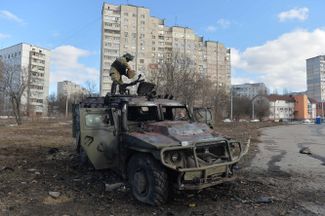 A soldier in Ukraine’s Territorial Defense Force inspects an armored vehicle damaged in