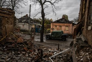 Украинский военный автомобиль среди поврежденных зданий в Купянске